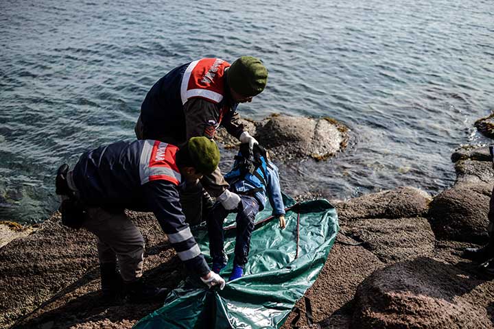 Dua polisi Turki mengangkat jenazah bocah laki-laki Suriah ke kantong mayat di pantai Canakkale, Bademli, Turki, kemarin.