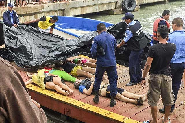 Anggota polisi dan Angkatan Laut menempatkan korban tewas di dermaga Corn Island, Nikaragua, sembilan mayat warga Kosta Rika yang meninggal dalam kecelakaan kapal di lepas pantai Little Corn Island pada tanggal 23 Januari 2016.
