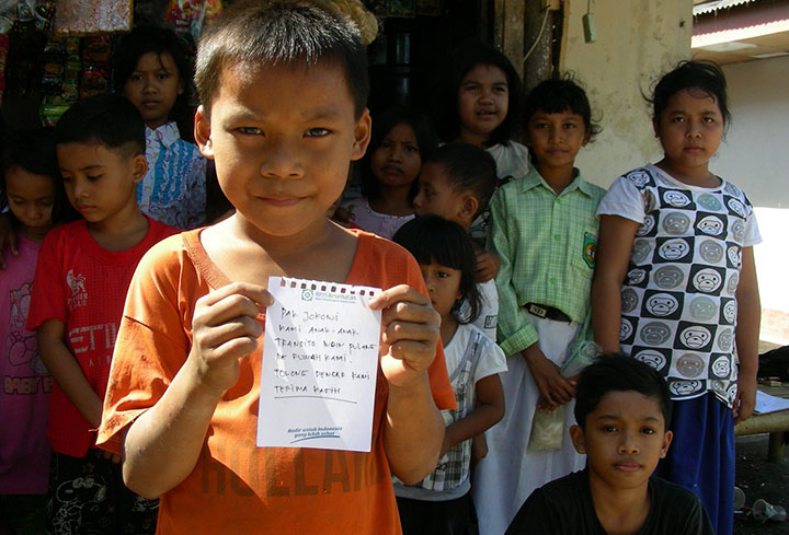 Barahim anak warga Ahmadiyah bersama teman sebayanya memegang secarik kertas yang berisi harapan kepada Presiden Joko Widodo.