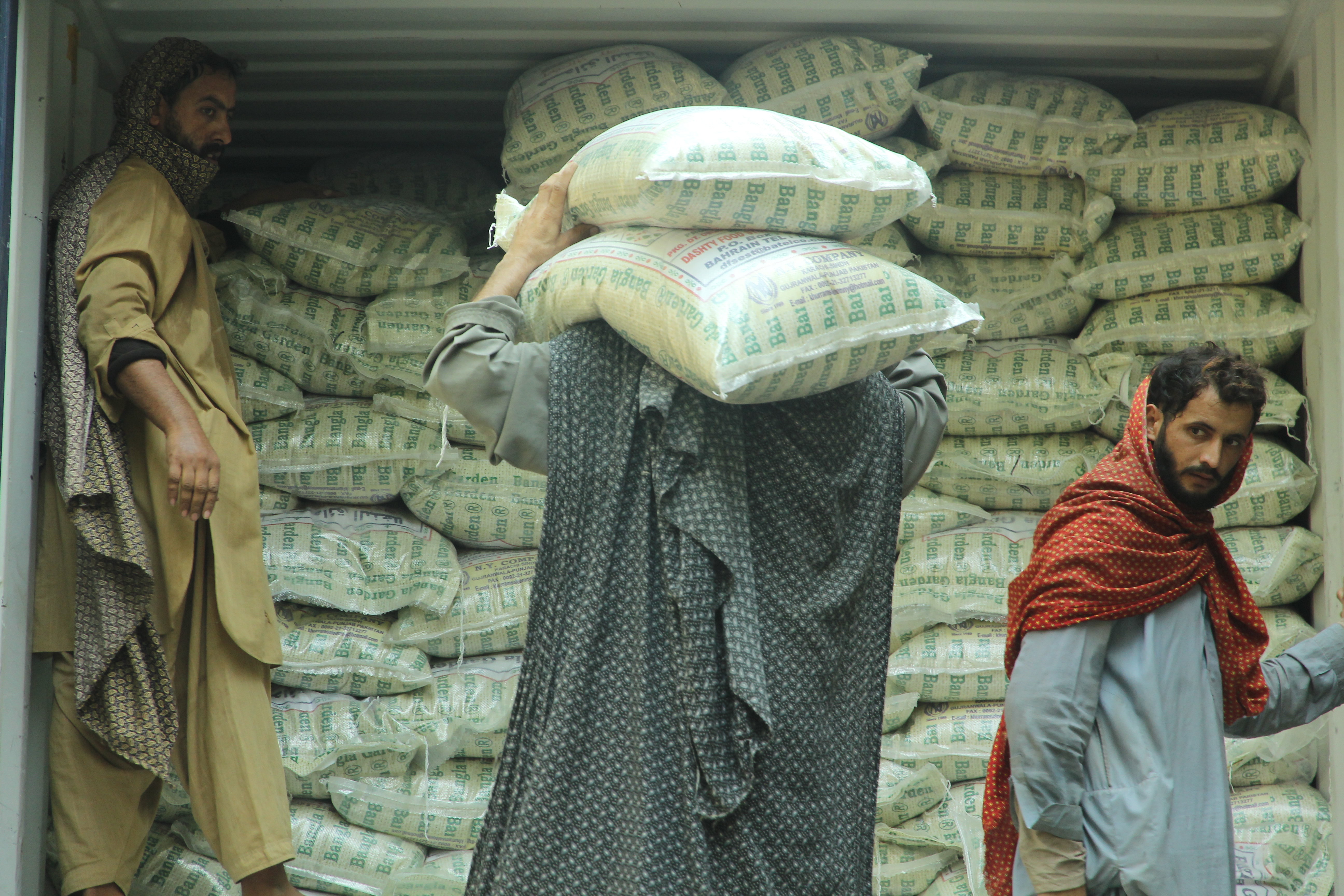 Para pekerja pabrik beras di SITE II Kawasan Industri Karachi sedang mengangkut beras ke dalam muatan truk kontainer, Jumat (10/11). Rencananya muatan ini untuk diekspor ke kawasan Eropa dan Amerika.