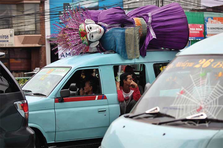 Pengamen mengangkut ondel-ondel menggunakan angkot sewaan menuju tempat ngamen di Jakarta Timur