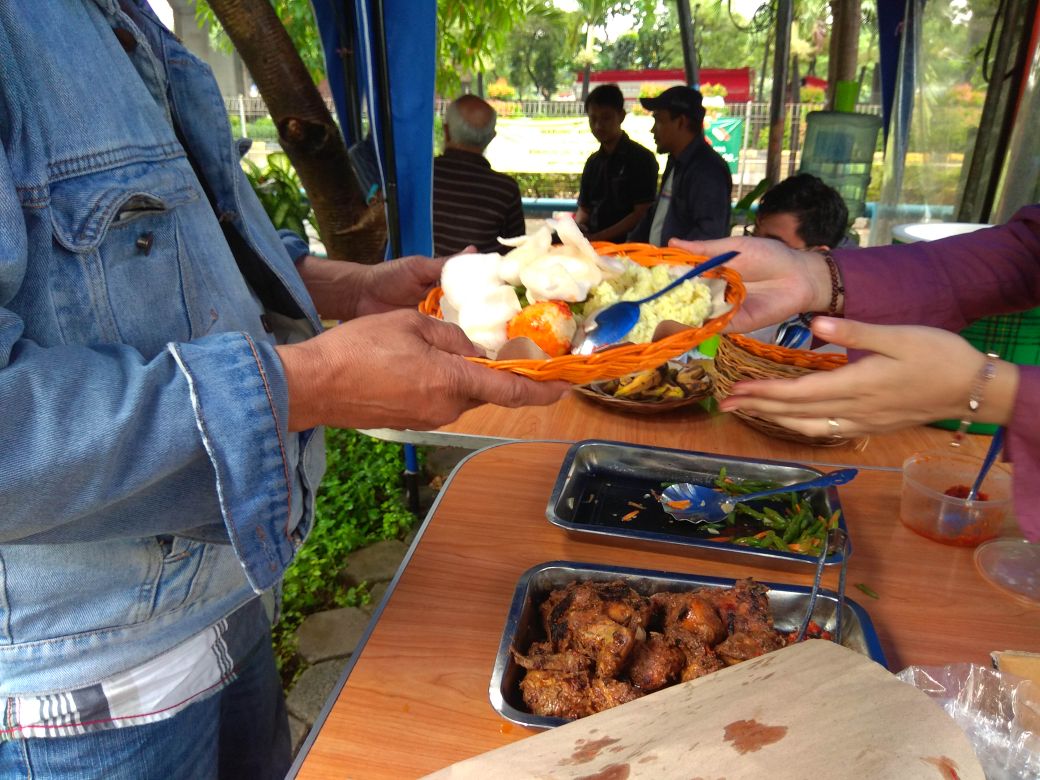 Pengunjung menikmati nasi kuning di warung Podjok Halal di area PT CMNP di Jalan Yos Sudarso Kavling 28, Jakarta Utara.