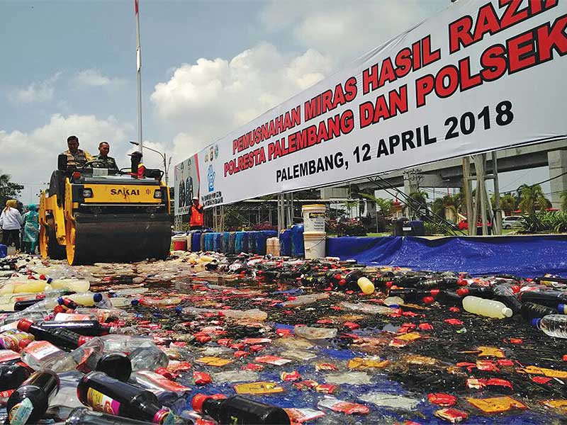 Alat berat menghancurkan ribuan botol minuman keras dalam pemusnahan barang bukti peredaran miras tanpa izin di Kantor Poresta Palembang, Sumsel, Kamis (12/4/2018)