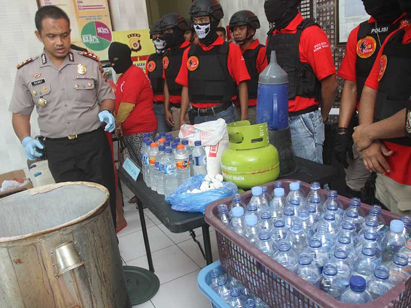 Kapolres Aceh Barat AKBP Raden Bobby Aria Prakarsa (kiri) memperlihatkan barang bukti dan pelaku peracik Minuman Keras (Miras) oplosan jenis CIU saat gelar perkara di Mapolres Aceh Barat, Aceh, Kamis (12/4/2018)