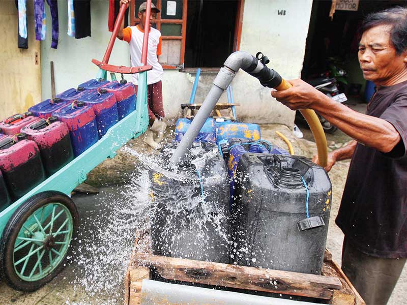 Penjual air bersih keliling mengisikan air ke dalam jeriken untuk disalurkan ke pelanggan di Penjaringan, Jakarta Utara, bulan lalu. 