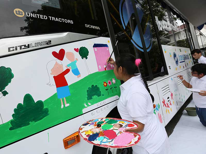 Para siswa berkebutuhan khusus dari Yayasan Art Brut Indonesia melukis badan bus Trans-Jakarta di depan Pendopo Balai Kota Jakarta, Jumat (20/4/2018)