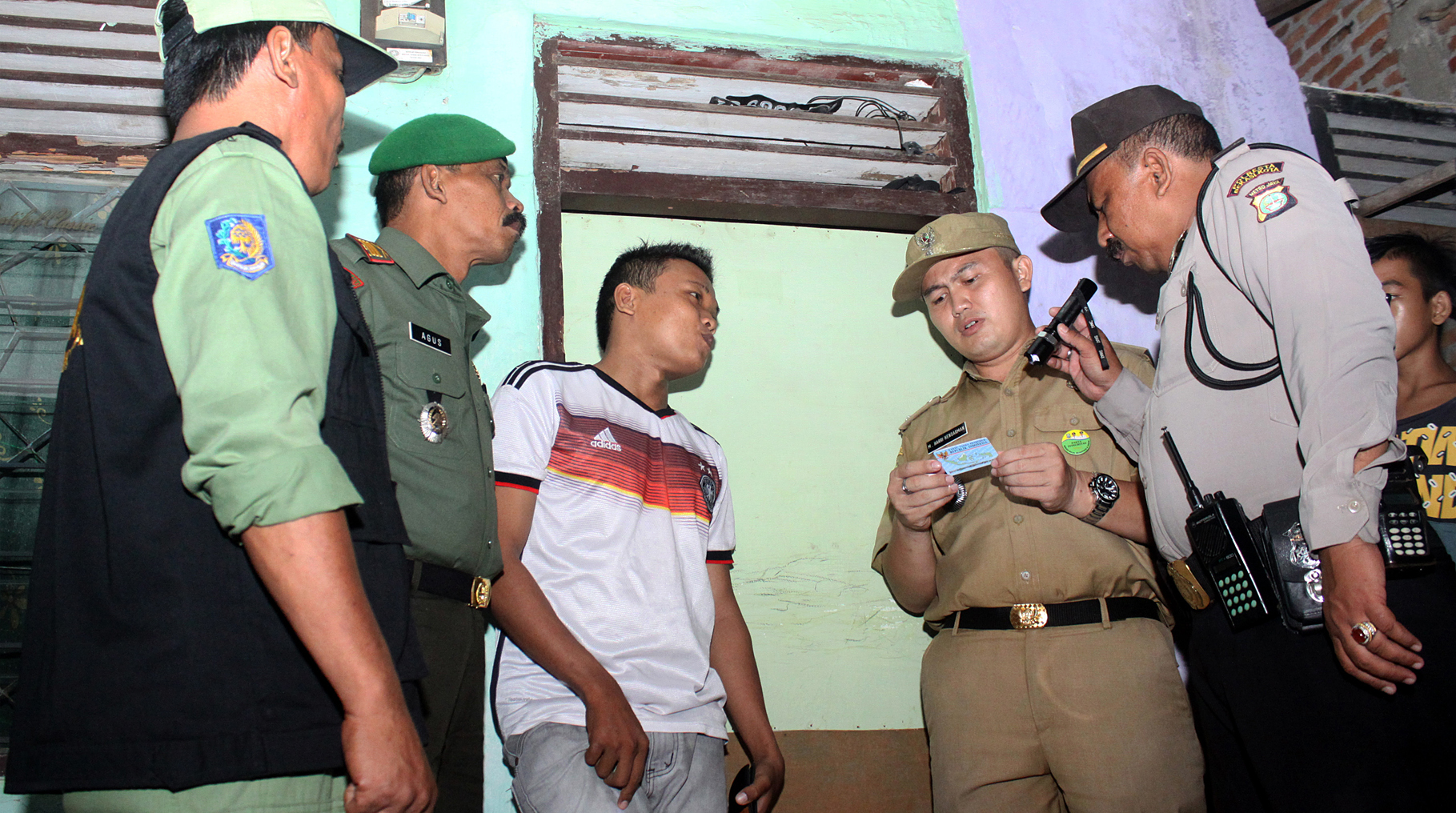 Petugas Kelurahan memeriksa kartu identitas seorang penghuni kontrakan saat menggelar operasi yustisi dan penyakit masyarakat di kawasan penduduk Margahayu, Bekasi, Jawa Barat, Rabu (20/1/2016).