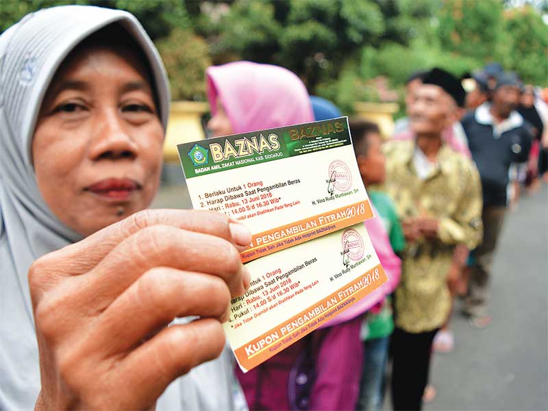 PEMBAGIAN ZAKAT FITRAH: Warga menunjukkan kupon untuk mengambil zakat fi trah berupa beras di pendopo Sidoarjo, Jawa Timur, kemarin. Sekitar 5.000 paket zakat fi trah dari pegawai Kabupaten Sidoarjo tersebut diberikan kepada masyarakat yang membutuhkan men