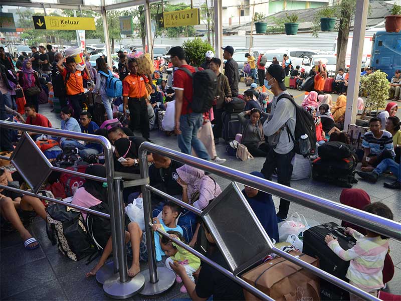 Para pemudik penguna jasa kereta api yang menunggu boarding duduk lesehan sepanjang koridor di Stasiun Pasar Senen, Jakarta Pusat