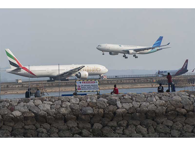 Sejumah wisatawan menyaksikan pergerakan pesawat di landasan pacu Bandara Ngurah Rai dari Pantai Patra Bali, Kuta