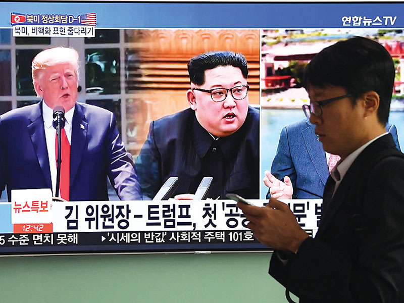 Warga melintas di depan layar televisi yang menayangkan gambar Presiden Amerika Serikat Donald Trump dan pemimpin Korea Utara Kim Jong-un di stasiun kereta di Seoul, Korea Selatan, kemarin. Kim dan Trump hari ini akan bertemu di Singapura sebagai upaya men