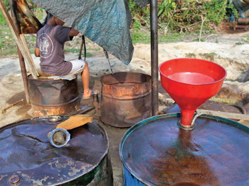 Penambang menyuling di lapangan sumur minyak di Aceh Timur.