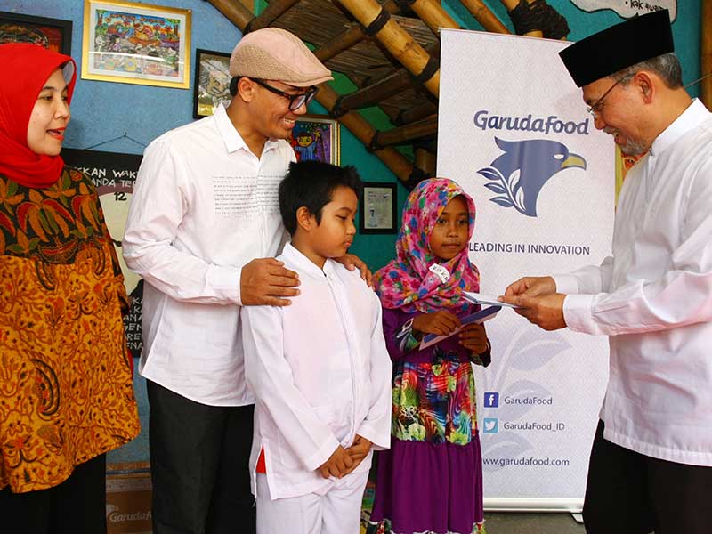 Director Garudafood Rudy Brigianto (kanan) dengan didampingi Head of Corporate Communication Garudafood Dian Astriana (kiri) dan Founder Kampung Dongeng Indonesia (Kado) Awaw Prakoso (kedua kiri) memberikan bingkisan kepada anak-anak marginal di Kampoeng D
