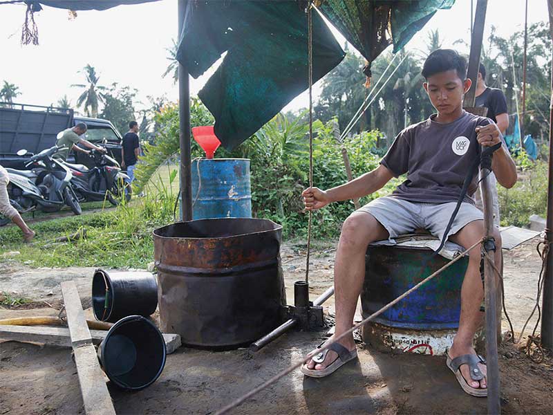 Seorang warga sedang memproses minyak mentah yang diambil dari pengeboran sumur minyak tradisional di Gampong Pasir Putih, Kecamatan Ranto Peureulak, Kabupaten Aceh Timur, pekan lalu.