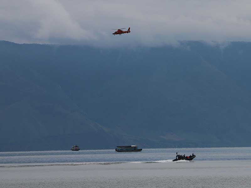  Helikopter Basarnas jenis Dauphin HR-3604 terbang di atas Danau Toba saat melaksanakan pencarian korban tenggelamnya KM Sinar Bangun, di Simalungun, Sumatera Utara, Sabtu (23/6/2018). 