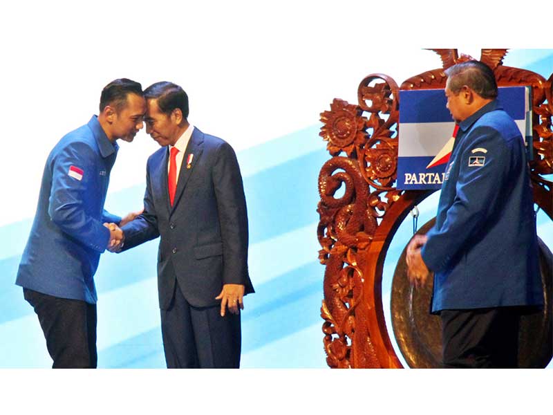 Presiden Joko Widodo (kedua kiri) berjabat tangan dengan Ketua Kogasma Partai Demokrat Agus Harimurti Yudhoyono (kiri) disaksikan oleh Ketua Umum Partai Demokrat Susilo Bambang Yudhoyono (kanan) saat membuka Rapat Pimpinan Nasional (Rapimnas) Partai Demokr