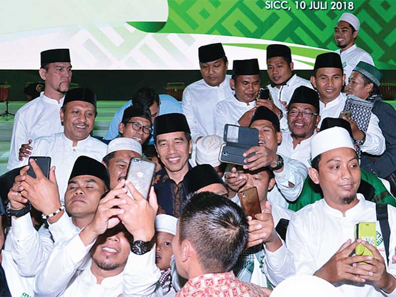 Presiden Joko Widodo dikerumuni ulama muda yang ingin berswafoto dengan dirinya saat Halalbihalal dan Silaturahim Nasional Solidaritas Ulama Muda Jokowi (Samawi) di Sentul, Babakan Madang, Kabupaten Bogor, Jabar, Selasa (10/7/2018)