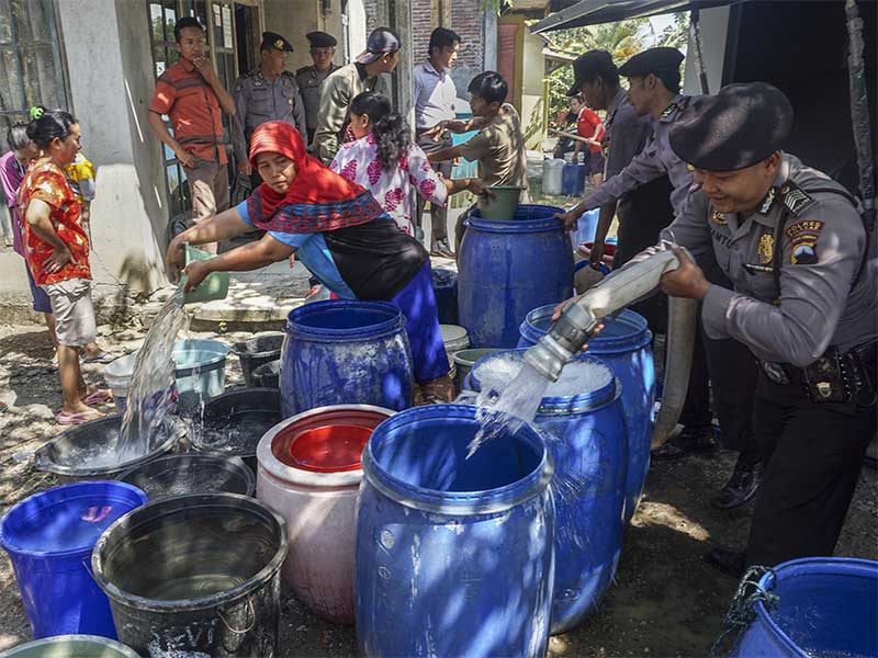 Sejumlah polisi Polres Cilacap memberikan bantuan air bersih dengan menggunkan kendaraan 