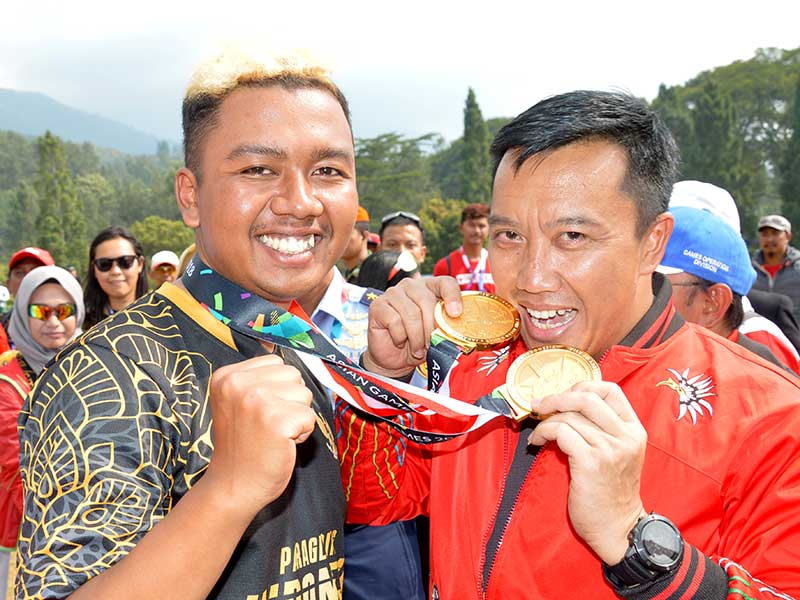 enpora Imam Nahrawi menggigit dua medali emas yang diraih atlet Jafro Megawanto, dari nomor ketepatan mendarat perorangan dan beregu putra cabang Paralayang Asian Games 2018 di Cisarua, Puncak, Bogor, Jawa Barat, Kamis (23/8/2018).