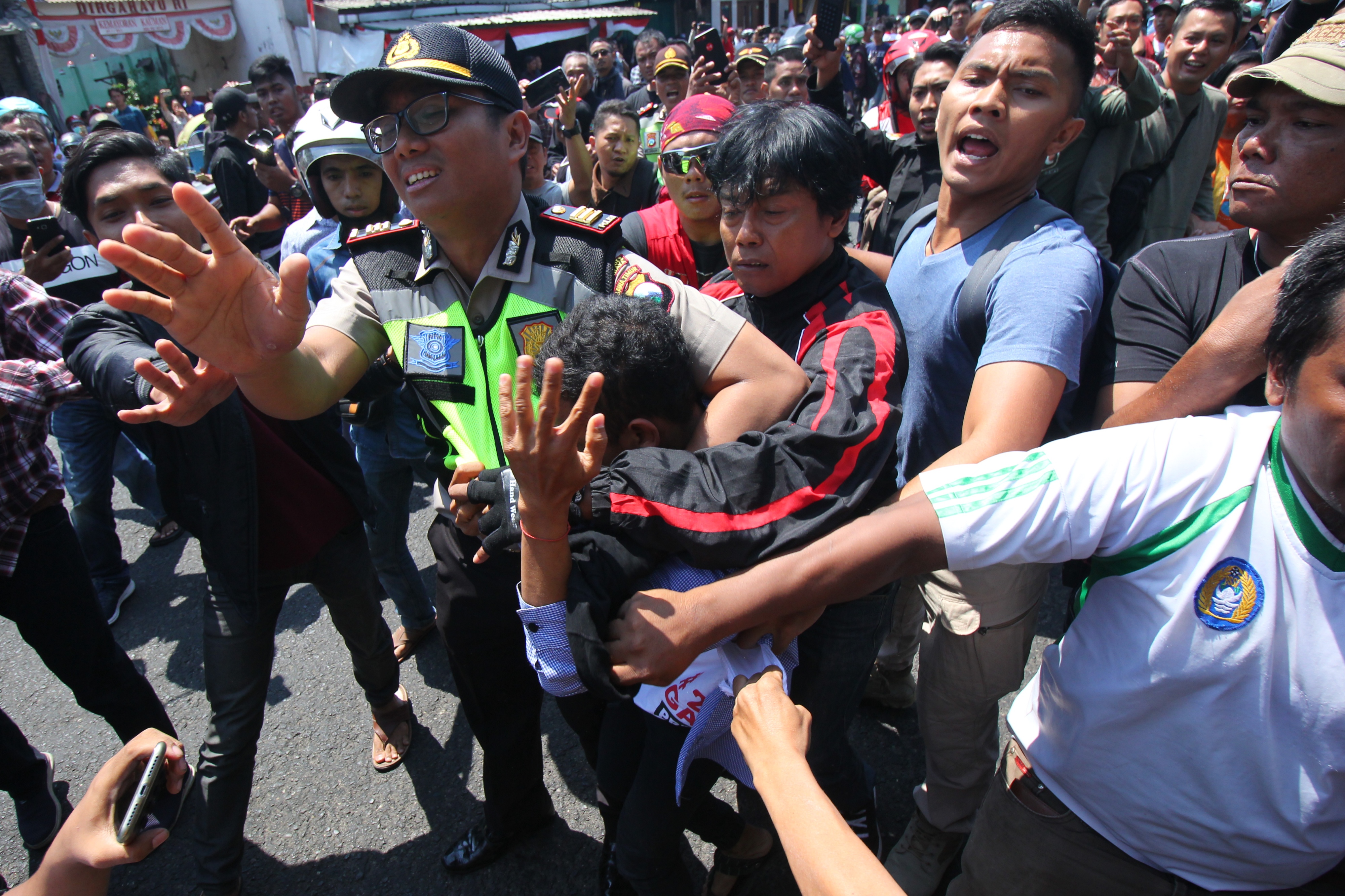 Polisi mengamankan seorang pemuda dari amukan massa saat aksi yang melibatkan dua kubu yang mendeklarasikan #2019 Ganti Presiden dan kubu yang menentang dan menyerukan cinta NKRI, di Jalan Indrapura, Surabaya, Jawa Timur, Minggu (26/8). 