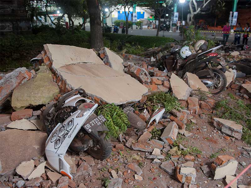 Sejumlah warga melihat reruntuhan bangunan akibat gempa yang menimpa kendaraan di salah satu pusat perbelanjaan di Denpasar, Bali, Minggu (5/8).