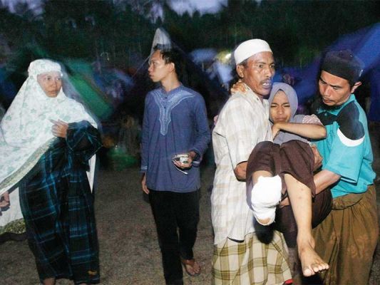 DIEVAKUASI KE POS KESEHATAN: Seorang korban gempa dievakuasi ke pos kesehatan wilayah karena mengalami demam saat mengungsi di halaman belakang Polsek Pemenang, Lombok Utara, NTB, kemarin. Karena hanya tersedia tenda dan penerangan minim, mereka memilih me