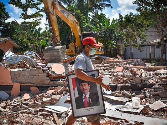 SEKOLAH RUSAK AKIBAT GEMPA: Warga memindahkan poster Presiden Joko Widodo dari bangunan SDN 2 Kekait yang rusak akibat gempa di Gunungsari, Lombok Barat, NTB, Minggu (12/8).