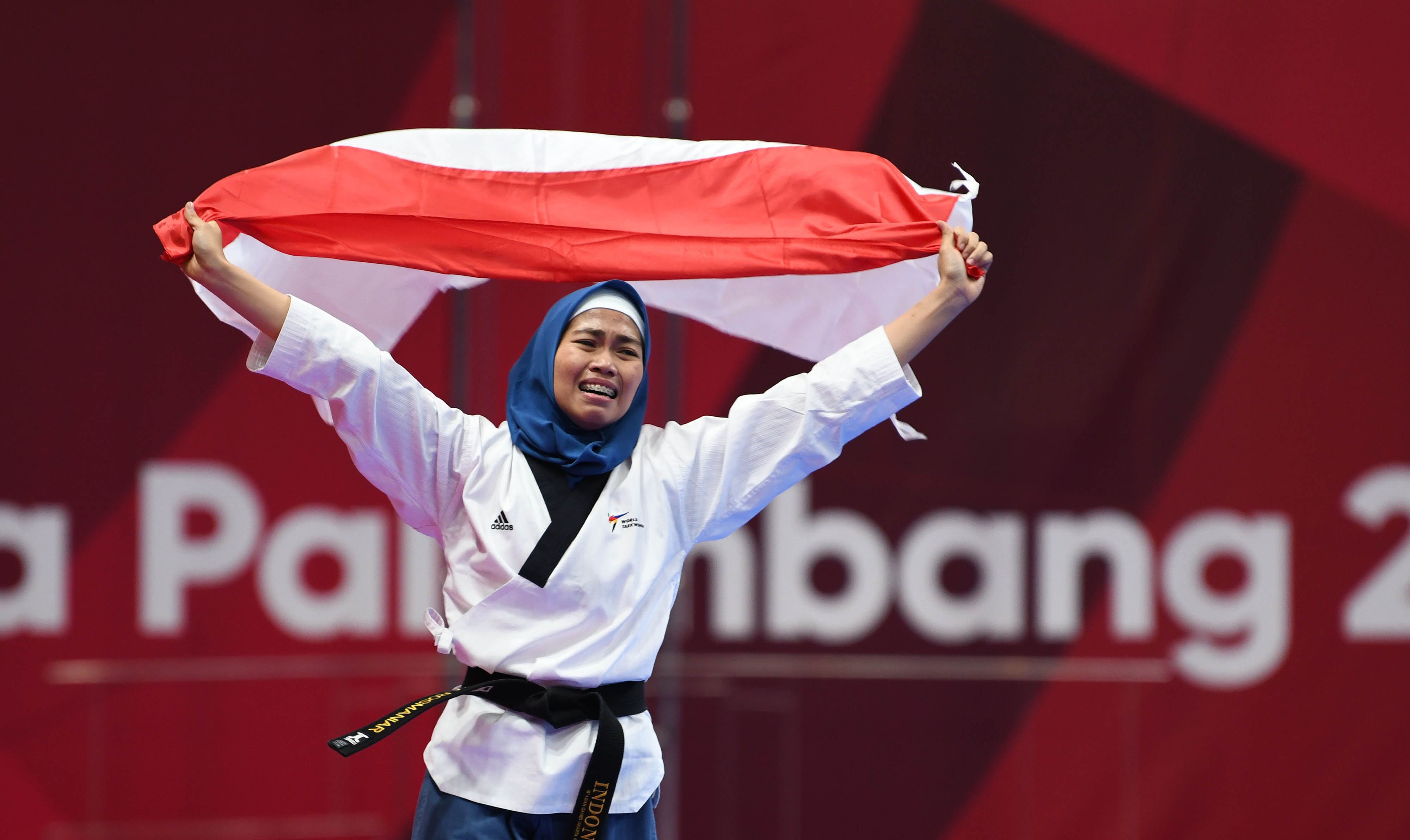 EMAS PERTAMA: Taekwondoin Indonesia Defi a Rosmaniar melakukan selebrasi kemenangan setelah mengalahkan atlet taekwondo Iran, Marjan Salahshouri, pada fi nal nomor poomsae individu putri Asian Games 2018 di Jakarta, kemarin.
