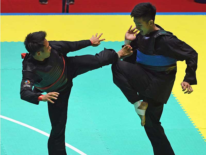 Pesilat Indonesia Komang Harik Adi Putra (kiri) melakukan tendangan ke arah pesilat Vietnam Tuan Anh Pham dalam babak semifinal Kelas E Putra Asian Games 2018 di Padepokan Pencak Silat Taman Mini Indonesia Indah (TMII), Jakarta, Minggu (26/8/2018). 