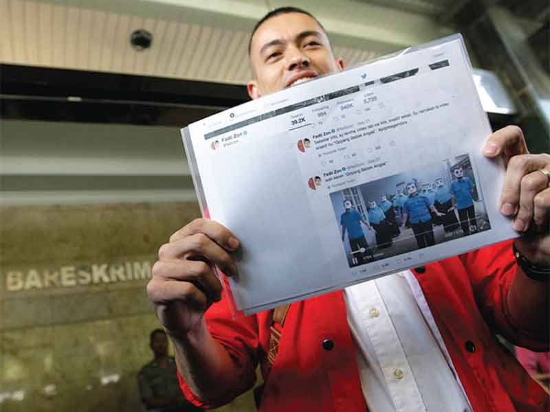 Kader Partai Solidaritas Indonesia (PSI) Rian Ernest menunjukkan salah satu bukti saat mendatangi Bareskrim Mabes Polri, Jakarta, Selasa (25/9/2018)