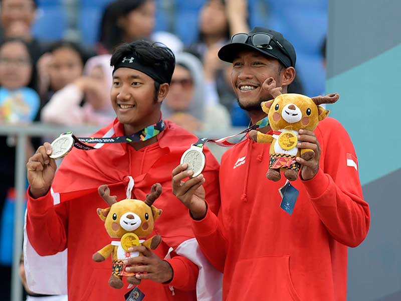 Pevoli Pantai pria Indonesia Mohammad Ashfiya (kiri) dan Ade Candra Darmawan berpose dengan medali perak usai babak final voli pantai pria Asian Games 2018 di arena Jakabaring Sport City, Palembang, Sumatera Selatan, Selasa (28/8/2018)