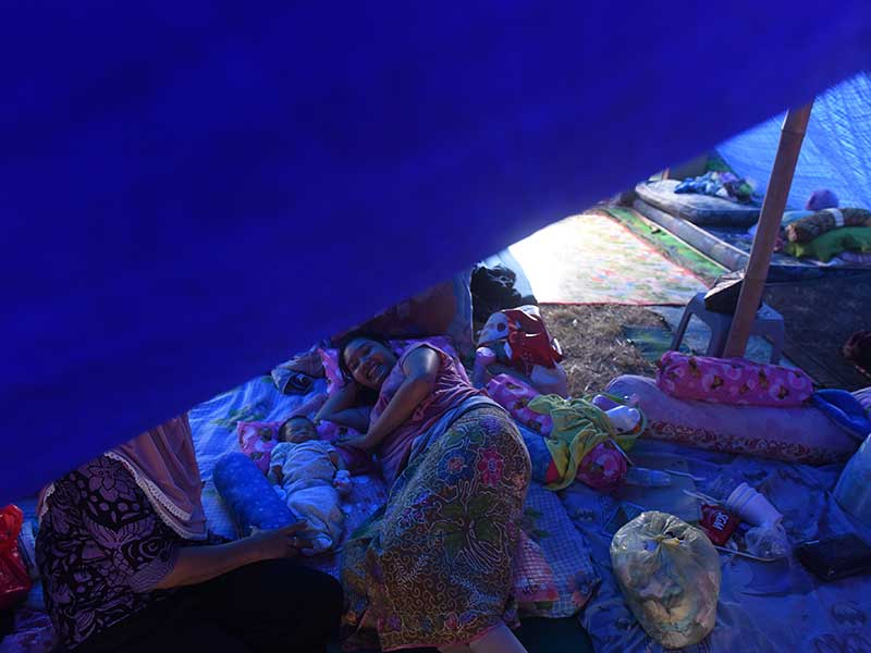 Vidianti (24) menidurkan anaknya yang berumur empat hari di tenda darurat pengungsian di Desa Santong, Kayangan, Lombok Utara, NTB, Sabtu (11/8/2018).