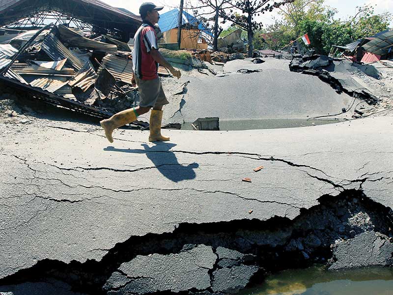 DAMPAK LIKUIFAKSI DI PETOBO: Warga melintas di kawasan perumahan yang porak-poranda di Petobo, Palu, Sulawesi Tengah, kemarin. Bangunan di perumahan tersebut sebagian besar rata dengan tanah akibat adanya likuifaksi.