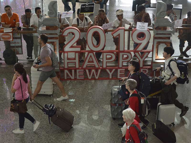 Sejumlah wisatawan membawa barang milik mereka setibanya di Bandara Internasional I Gusti Ngurah Rai, Bali, Kamis (27/12/2018). 
