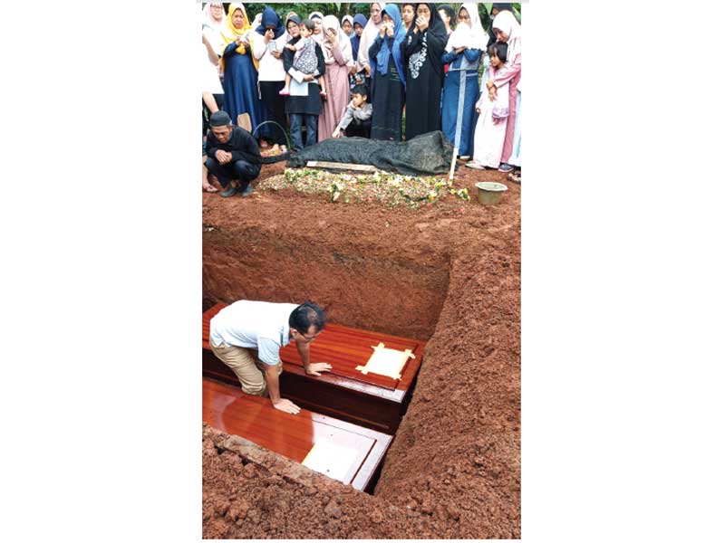 PEMAKAMAN KORBAN TSUNAMI: Karyawan PLN Agus Wibowo mengazani kedua anaknya, Rifda Zarina Mecca dan Zaki Arinal Haq, yang dimakamkan di samping pusara sang ibu di TPU Sawangan Lama, Pengasinan, Depok, kemarin. Agus dan keluarga yang sedang mengikuti family 