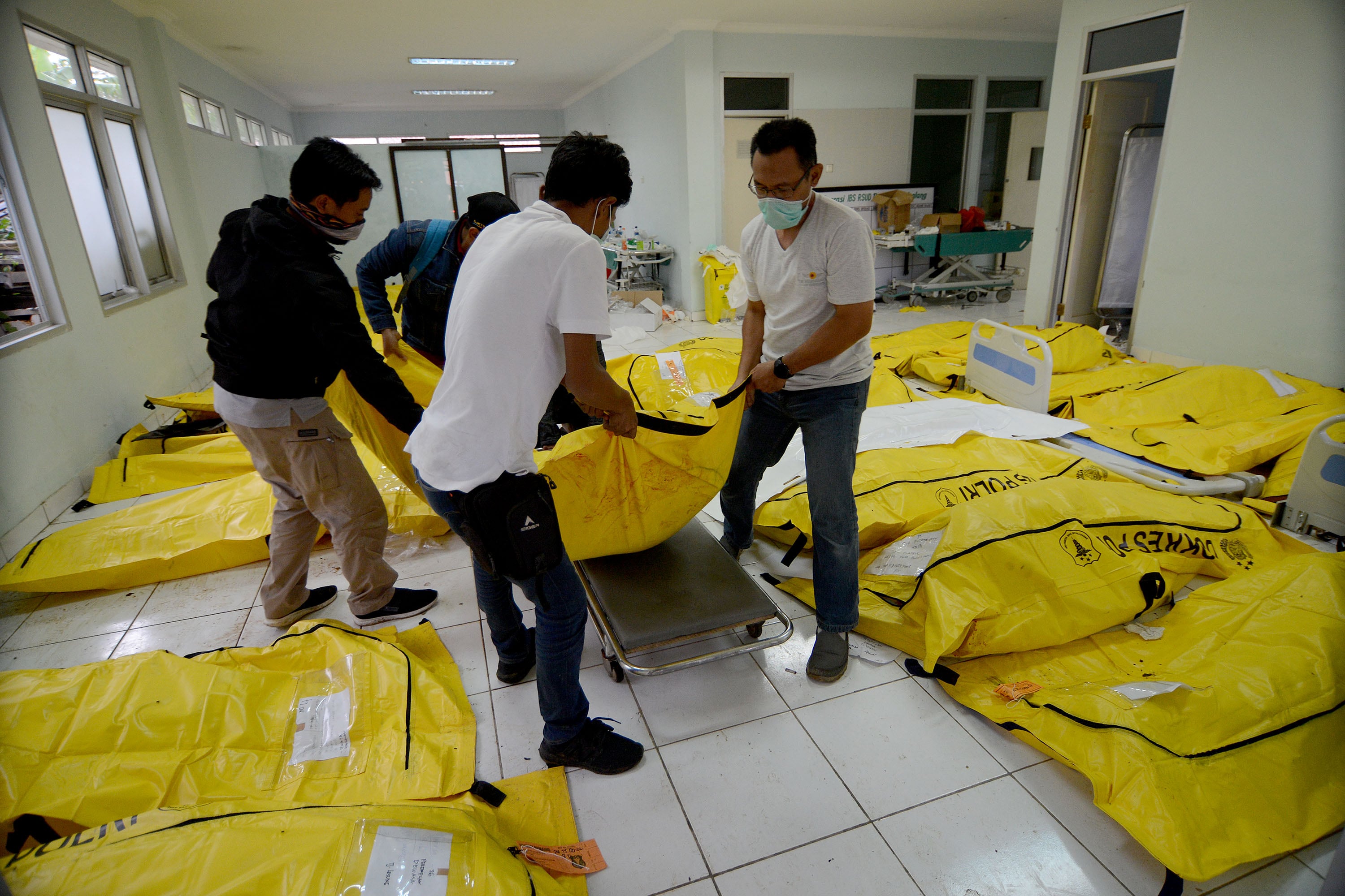 Petugas memindahkan jenazah yang telah teridentifikasi untuk dikembalikan ke keluarga di lokasi sementara di RSUD Berkah, Pandeglang, Banten, Senin (24/12).