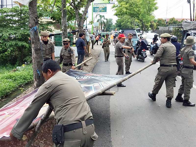 PENERTIBAN ALAT PERAGA KAMPANYE: Satpol PP menurunkan alat peraga kampanye (APK) yang melanggar aturan, seperti ditempelkan di pohon serta di taman-taman kota. 