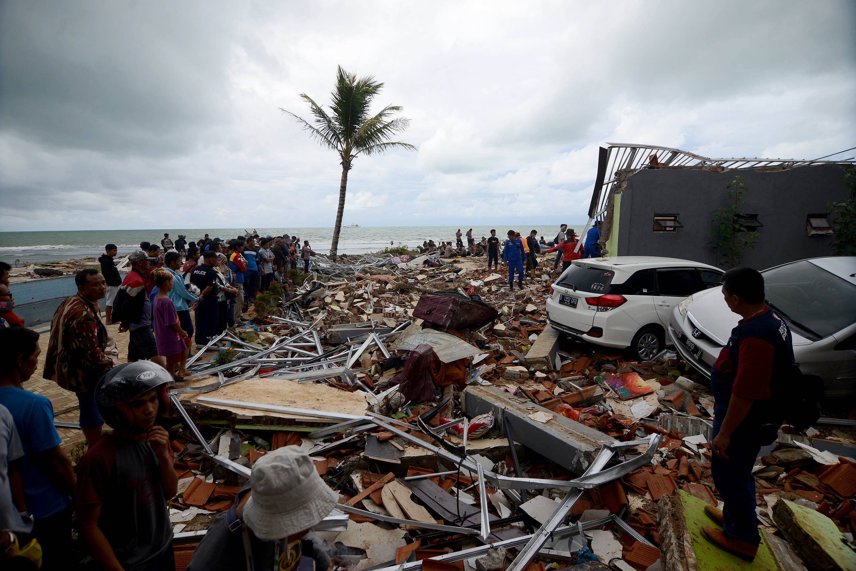 Warga menyaksikan tim dan relawan mengevakuasi dugaan korban yang tertimbun bangunan di Hotel Stephani, Anyer, Banten, Senin (24/12). 