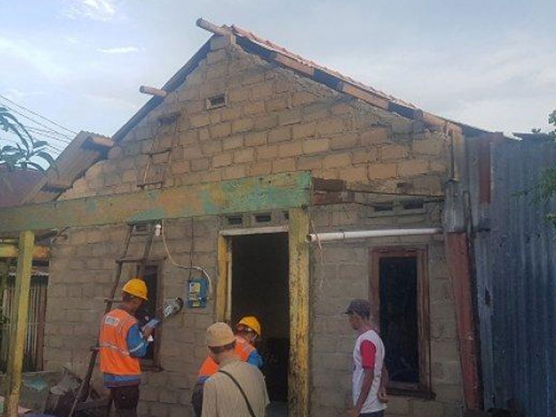 Petugas teknisi rekanan PLN tengah memperbaiki jaringan listrik di rumah warga