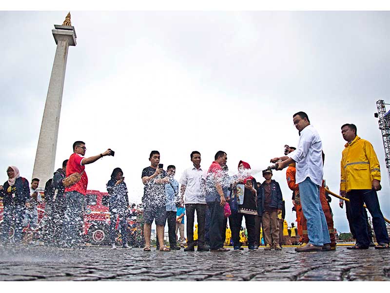 Gubernur DKI Jakarta Anies Baswedan (kedua kanan) bersama petugas Dinas Lingkungan Hidup (DLH) DKI Jakarta membersihkan kawasan Monumen Nasional (Monas) di Jakarta, Selasa (1/1/2019).