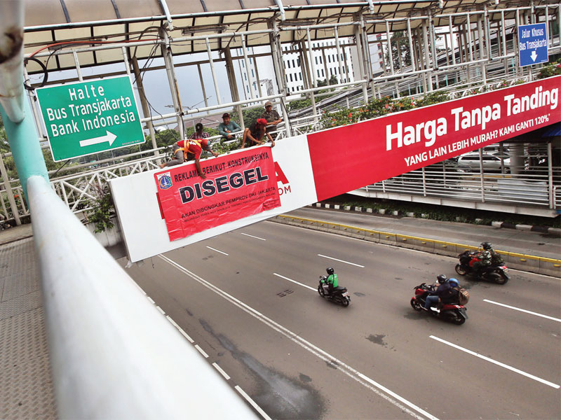 Petugas Satpol PP menyegel iklan yang terpasang di JPO kawasan MH Thamrin, Jakarta, Selasa (22/1). Reklame yang disegel itu melanggar Perda DKI Jakarta Nomor 9 Tahun 2014 tentang Penyelenggaraan Reklame. Selanjutnya Pemprov DKI Jakarta akan mengganti rekla