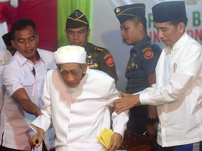 Presiden Joko Widodo (kanan) menuntun Pimpinan Pondok Pesantren Al-Anwar Sarang KH Maimoen Zubair (tengah) saat menghadiri acara Sarang Berzikir untuk Indonesia Maju di Rembang, Jawa Tengah, Jumat (1/2/2019)