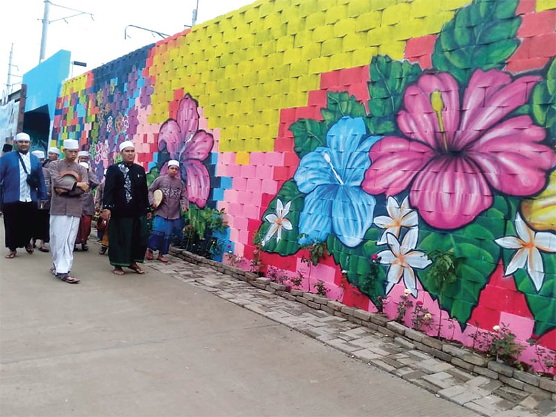 Warga melintas di samping mural tembok terowongan lintasan kereta api di Kelurahan Tanah Tinggi, Kecamatan Tangerang, Kota Tangerang, Sabtu (2/2)