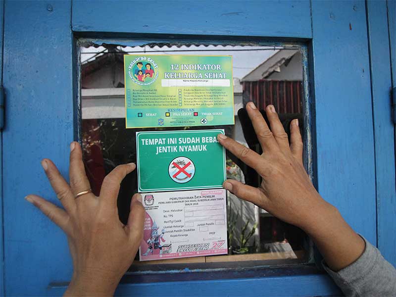  Seorang kader Ibu Memantau Jentik (Bumantik) menempelkan stiker bebas jentik nyamuk di salah satu rumah warga saat Gerakan Pemberantasan Sarang Nyamuk di Surabaya, Jawa Timur, Jumat (1/2/2019). 