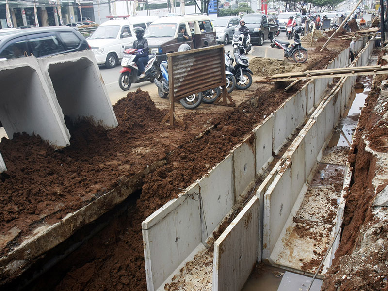 BONGKAR PASANG PEMBANGUNAN SALURAN DRAINASE MARGONDA: Warga melintas di dekat proyek pembangunan ulang saluran drainase di Jalan Margonda Raya, Depok, Jawa Barat, Jumat (30/9). 
