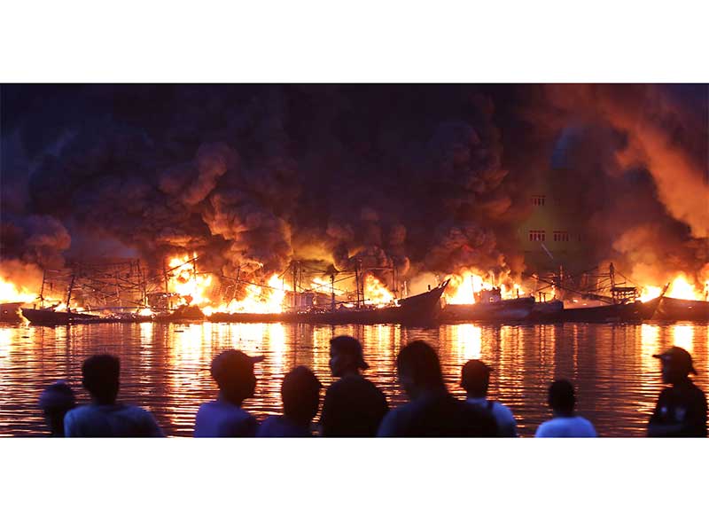 Warga melihat kapal-kapal nelayan terbakar di Pelabuhan Muara Baru, Jakarta, Sabtu (23/2/2019). 