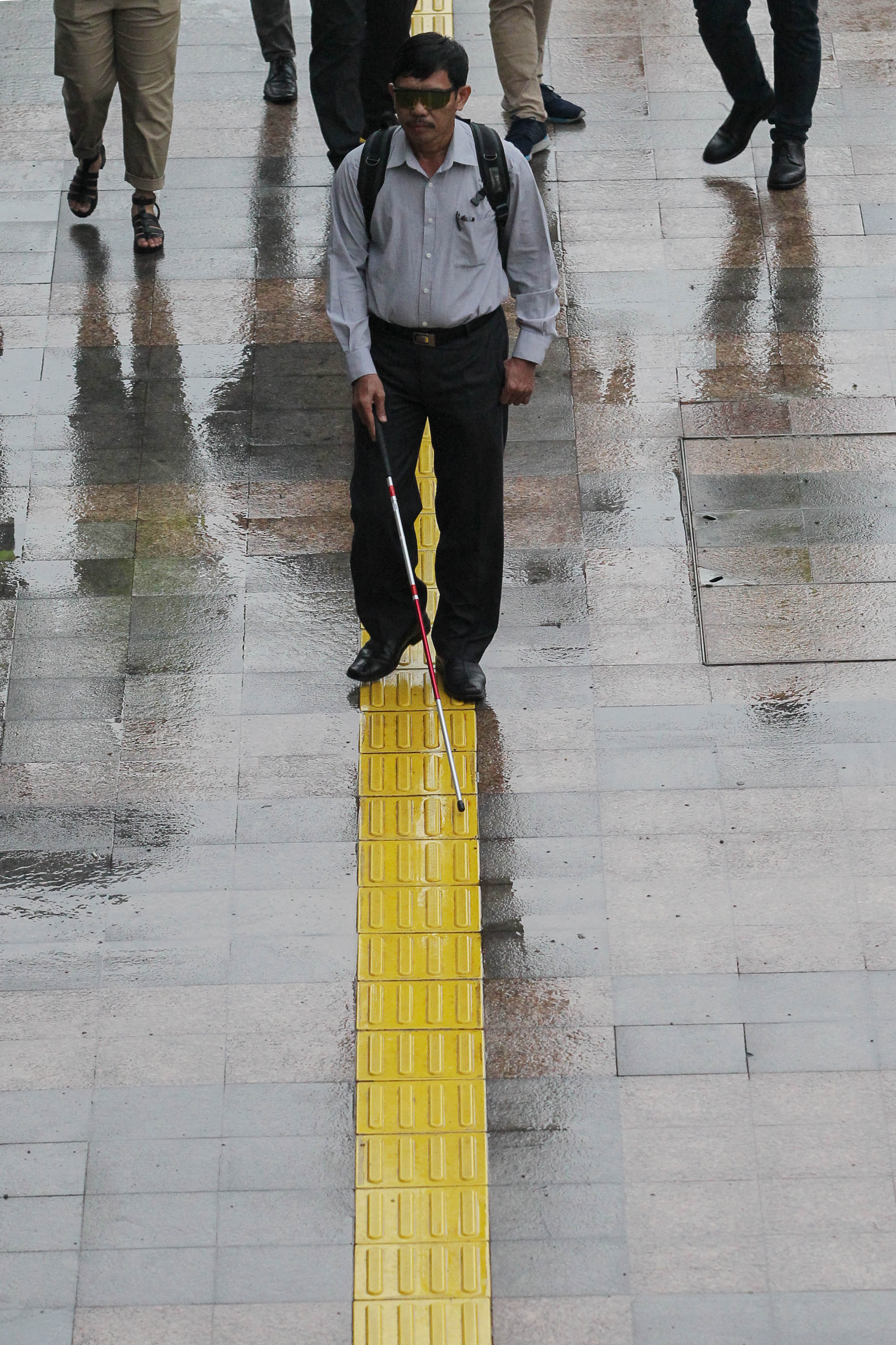 pejalan kaki melakukan uji coba fasilitas umum ramah disabilitas di trotoar Dukuh Atas, Jalan Sudirman