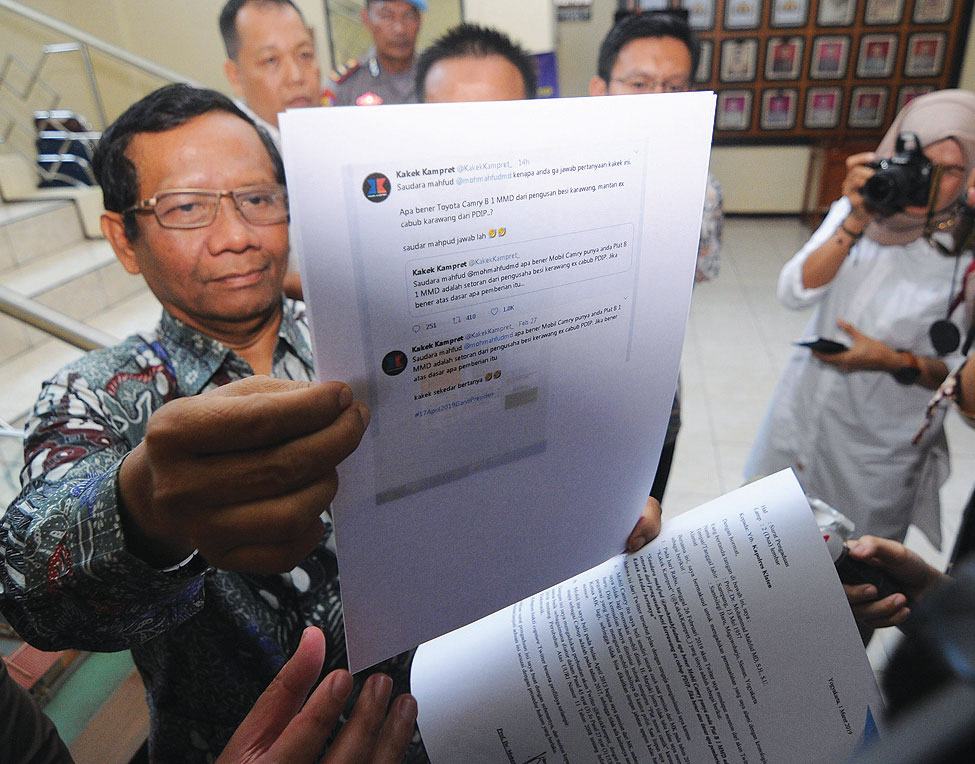 Mantan Ketua Mahkamah Konstitusi Mahfud MD (kiri) menunjukkan barang bukti print dari media sosial di Polres Klaten, Jawa Tengah, kemarin. Mahfud MD melaporkan akun Twitter atas nama @KakekKampret_ terkait dengan kasus pencemaran nama baik dirinya.