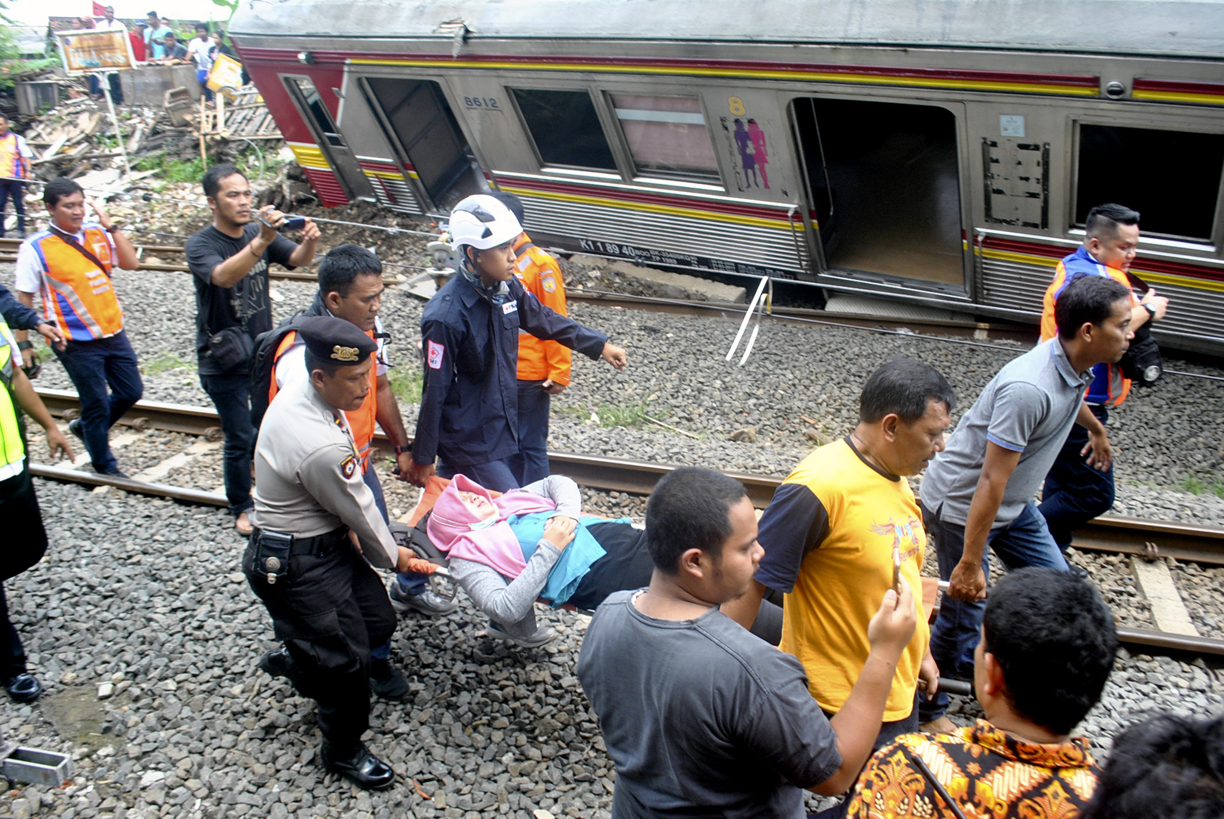Petugas membawa korban KRL Commuter Line 1722 yang anjlok di pintu perlintasan Kebon Pedes, Tanah Sareal, Kota Bogor, Jawa Barat, Minggu (10/3).