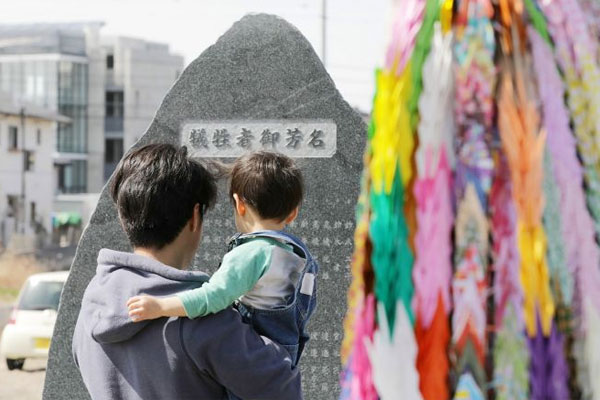 Seorang warga melihat monumen berisi nama korban gempa dan tsunami 2011 yang melanda Iwaki, Prefektur Fukushima, dalam perungatan delapan ta